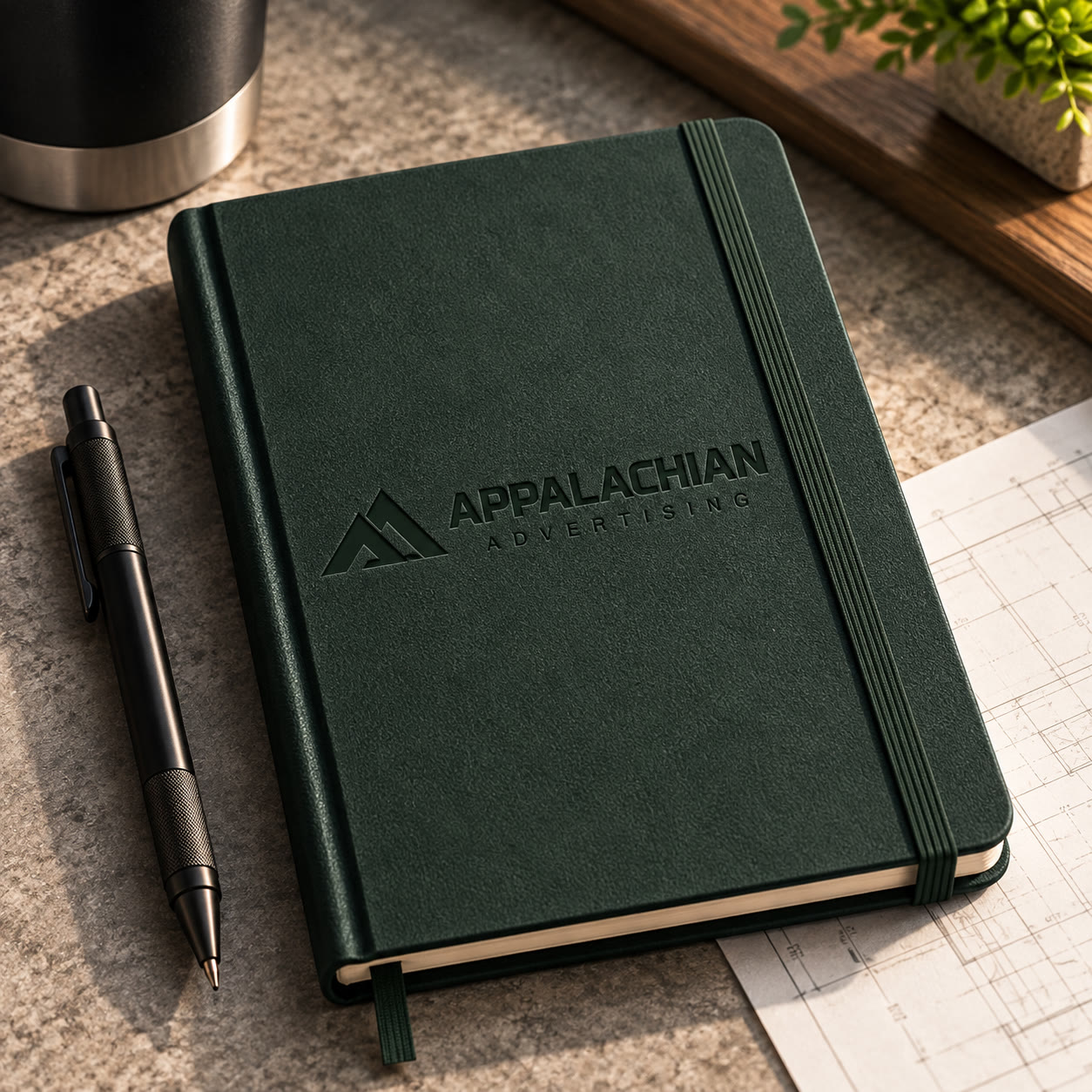 A Spruce leather notebook with the horizontal lockup blind-debossed on the cover.